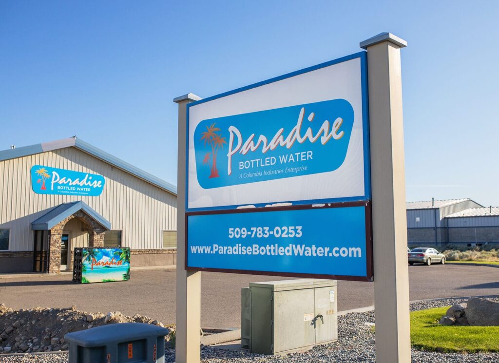 Paradise Bottled Water Sign Outside with their Building in the background.